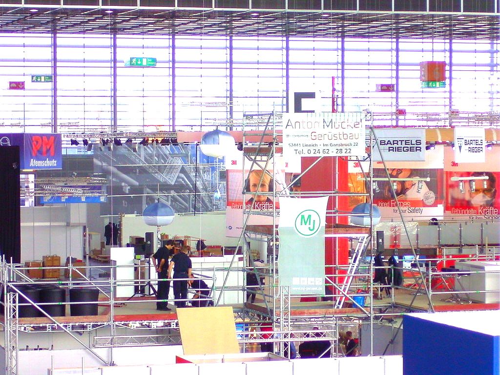 Messehalle im Aufbau, Gerüstlagen mit dem Banner von Anton Muckel Gerüstbau über den Standflächen